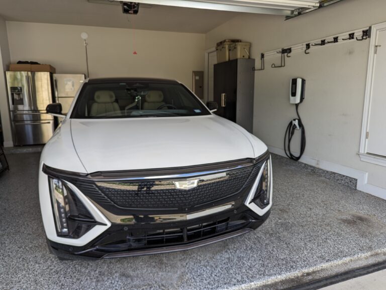Cadillac Lyriq parked in a garage beside a wall-mounted Level 2 charger