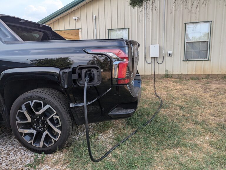 Chevrolet Silverado EV charging from an outdoor charger on a metal building
