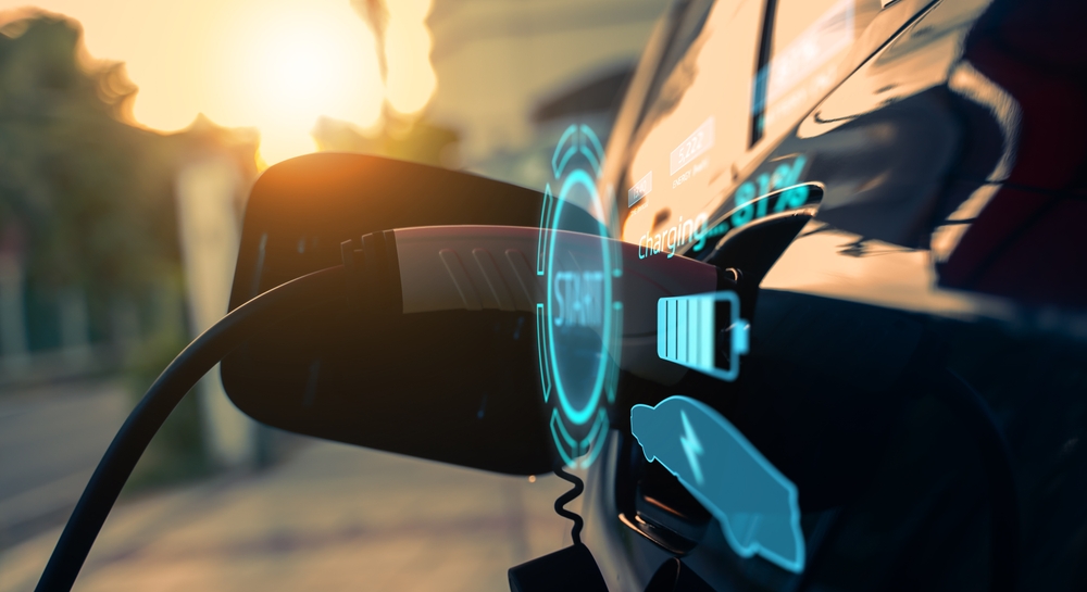 Close-up of an EV charging cable plugged into a car at golden hour sunset, with glowing holographic-style HUD graphics overlay showing 'Charging START', a battery icon at 31%, and charging stats. The warm sunlight reflects off the car's glossy red paint, creating a futuristic and eco-friendly vibe. Perfect for electric vehicle enthusiasts!