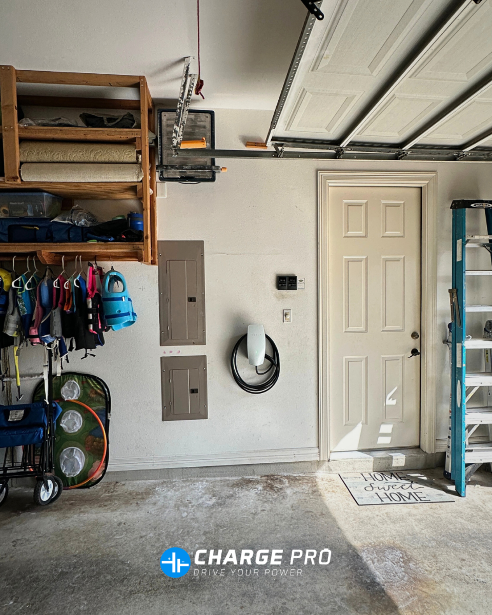 Wall-mounted Tesla home EV charger installed next to electrical panels inside a residential garage by ChargePro Texas.