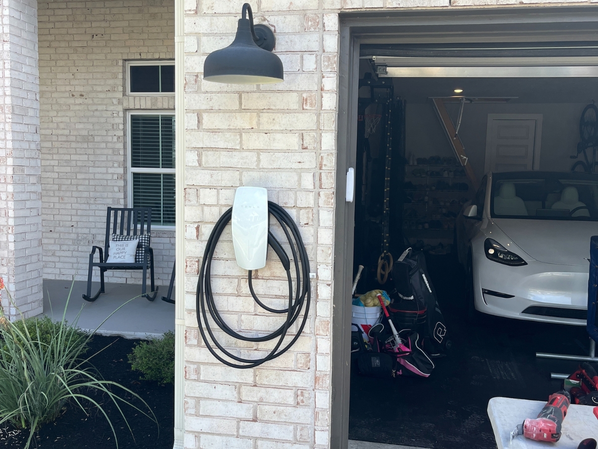 EV charger mounted on exterior brick beside a garage door
