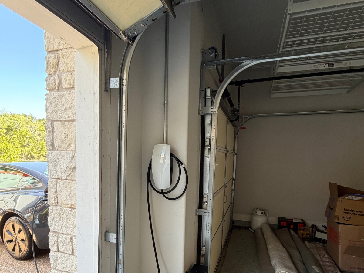 Conduit run above a garage door feeding a wall-mounted EV charger