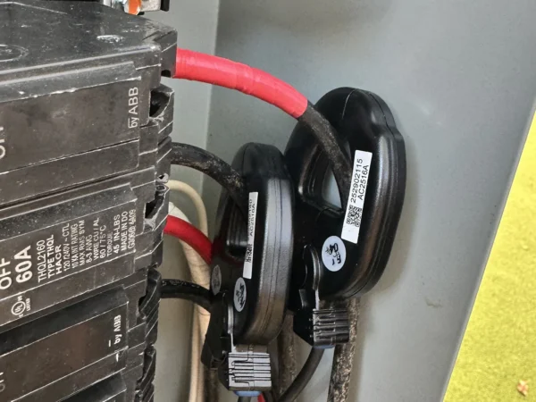 Current transformer (CT) sensors clamped around the main conductors in a residential panel for EV charger dynamic load management