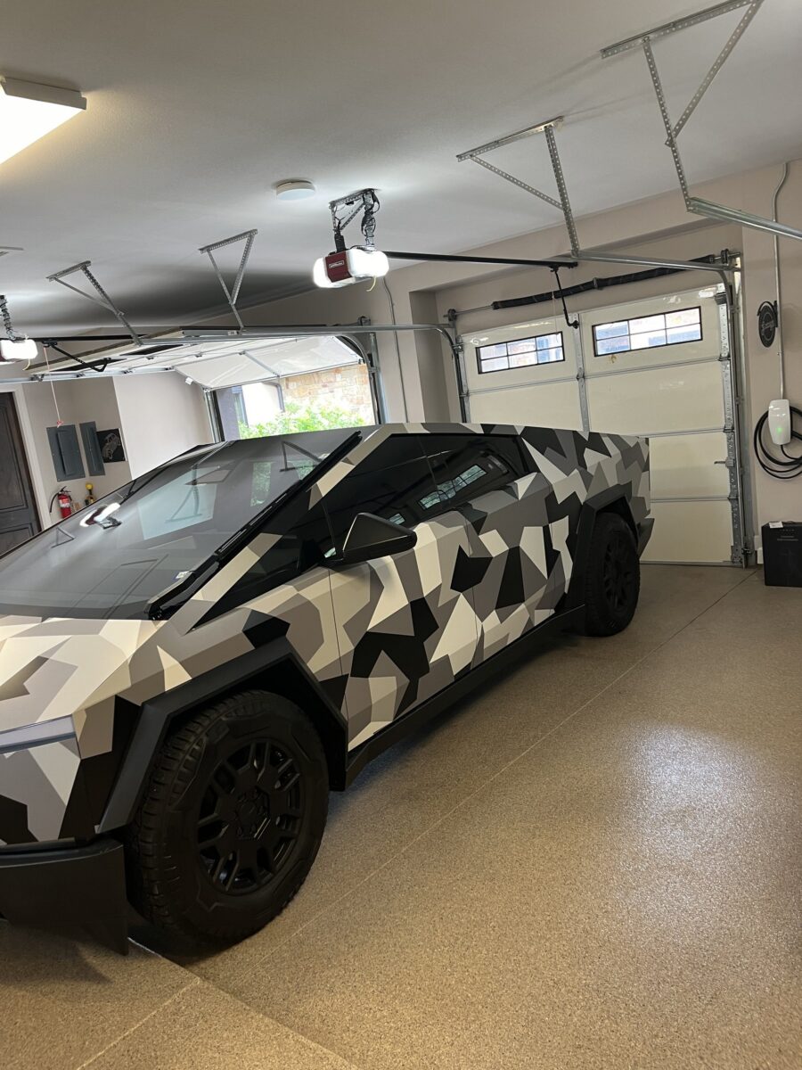 Tesla Cybertruck parked beside a garage-mounted Tesla Wall Connector