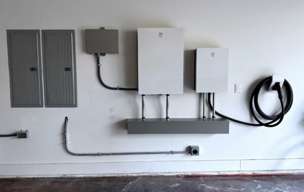 GM Energy V2H home hub, inverter and PowerShift charger installed on a garage wall beside the electrical panels