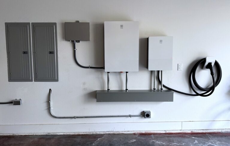 GM Energy V2H home hub, inverter and PowerShift charger installed on a garage wall beside the electrical panels